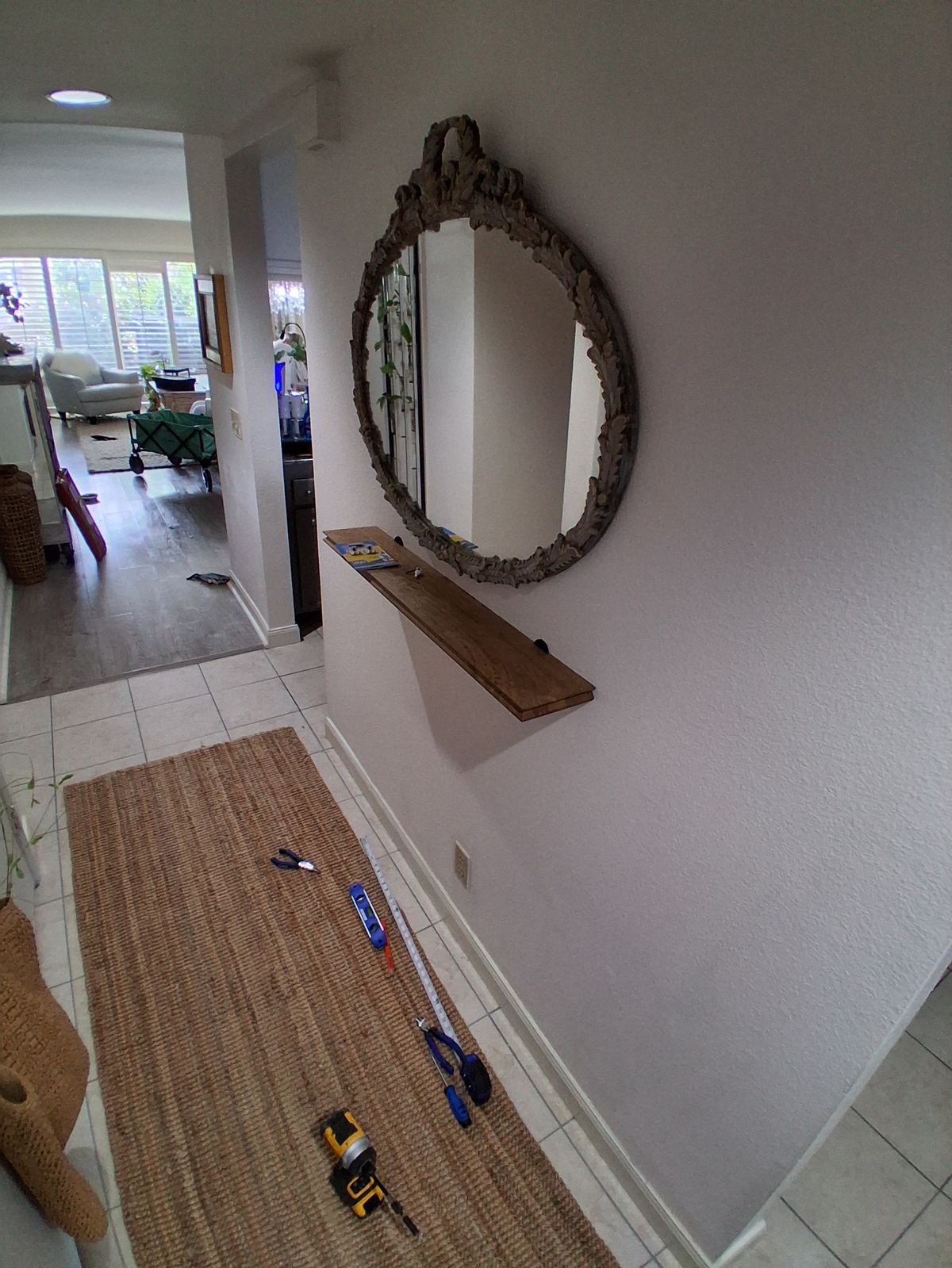 Decorative mirror and floating shelf mounted in hallway